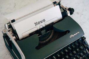 Schreibmaschine mit einem eingelegten Blattpapier, auf dem "News" steht.