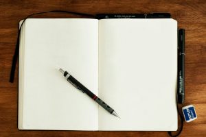 AUfgeschlagenes Notizbuch und Stifte