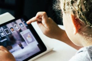 Ein Kind tippt ein Icon auf einem Tablet an.