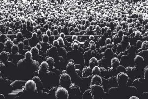 Schwarz-weiß-Aufnahme: Sitzende Menschenmenge von hinten